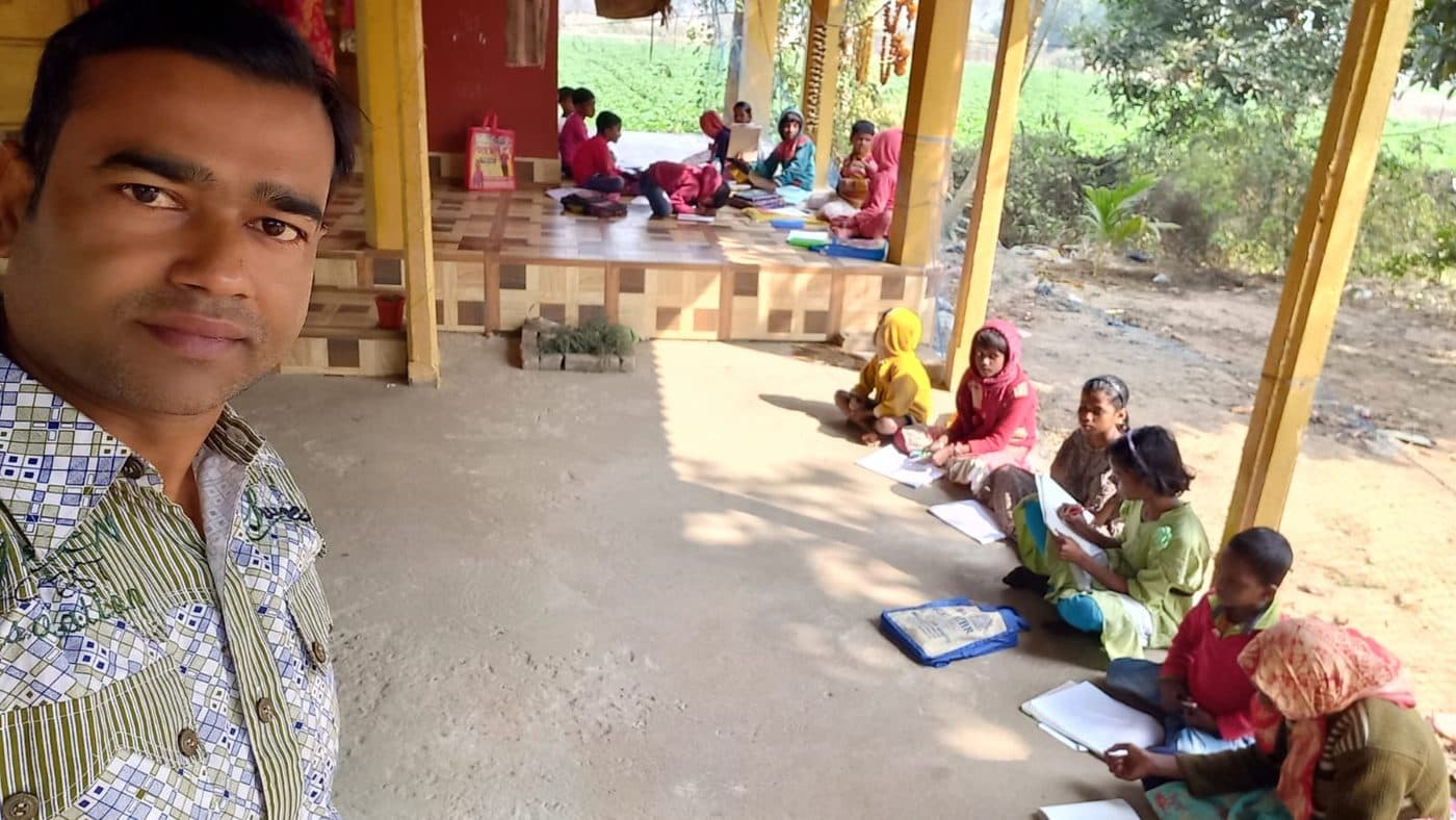 গ্রামের পাঠ — বারান্দায় পড়াশোনা, পেছনে ক্ষেত।